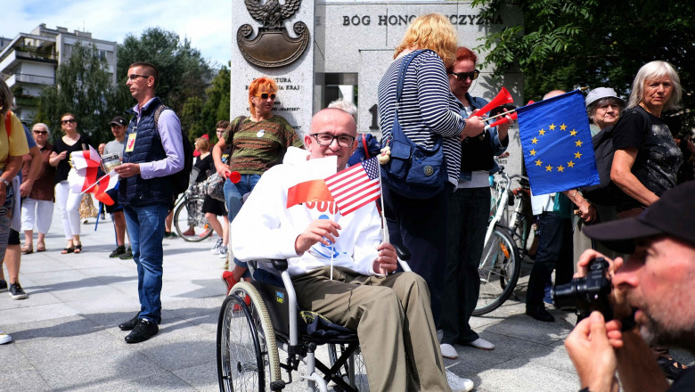 Protestatari în Polonia. În centru, un bărbat în scaun cu rotile care ține în mâini un steag al SUA