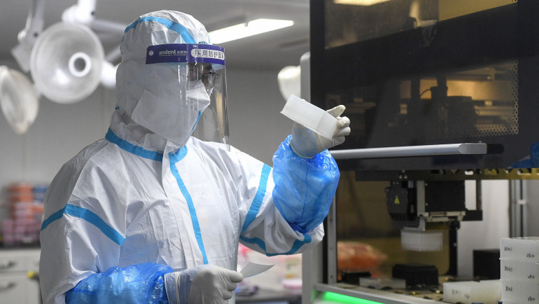 Laboranţi poartă costume de protecţie în timp ce fac teste asupra unor mostre contaminate cu COVID-19 într-un laborator din Wuhan, China.
