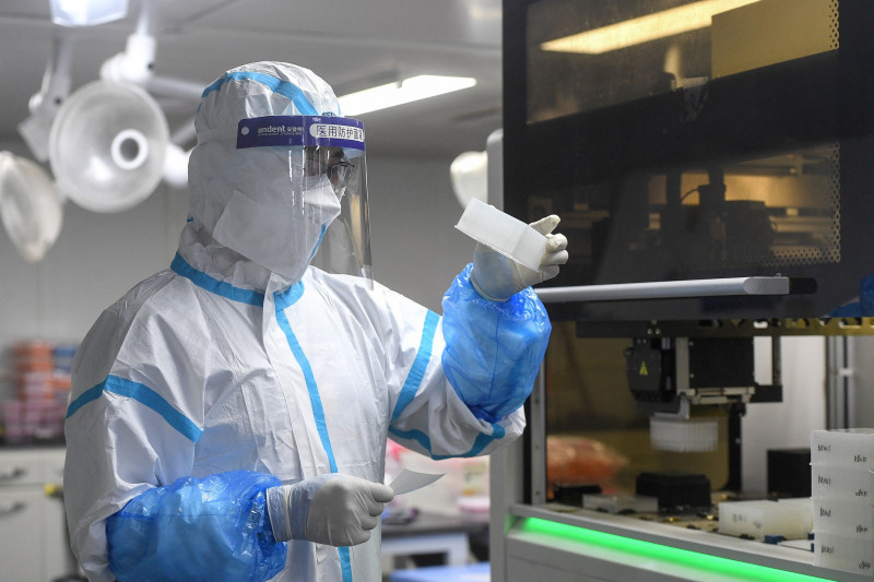 Laboranţi poartă costume de protecţie în timp ce fac teste asupra unor mostre contaminate cu COVID-19 într-un laborator din Wuhan, China.