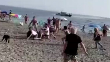 Oameni care aleargă un bărbat pe plajă.