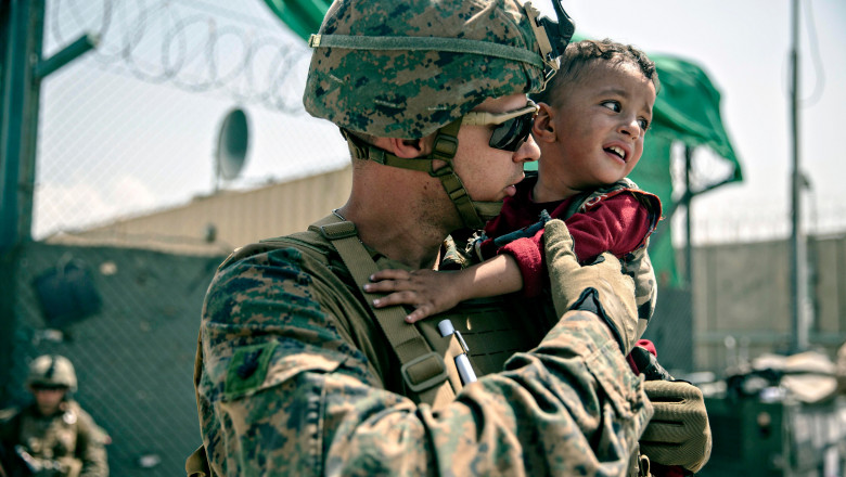 soldat cu un copil in brate pe aeroportul din kabul
