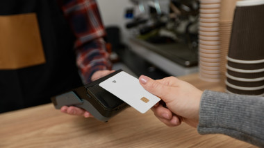 customer hand holding credit card near nfc terminal.