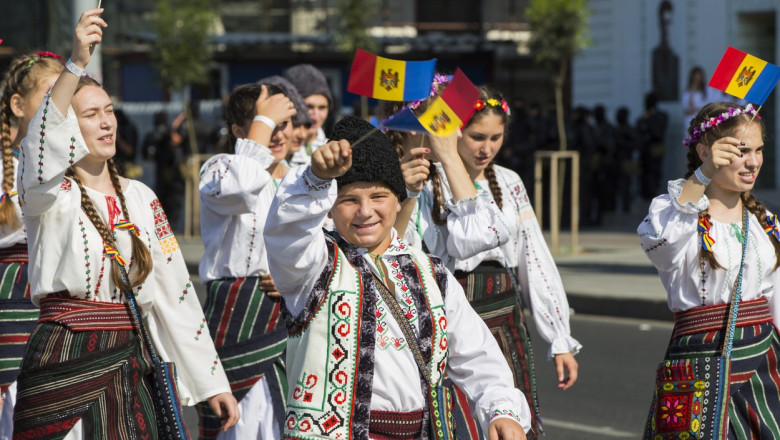 tineri in costume populare defiland in mana cu stegulete ale republicii moldova