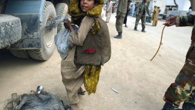 copil afgan incarcat cu marfa de contrabanda langa un camion