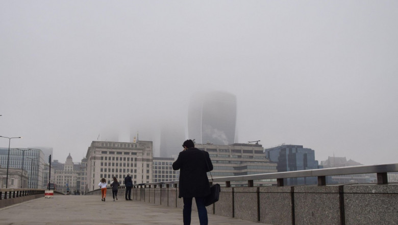 oameni merg pe stradă prin Aer poluat în Londra.