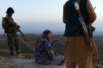 O femeie cu capul acoperit vorbește cu bărbați înarmați
