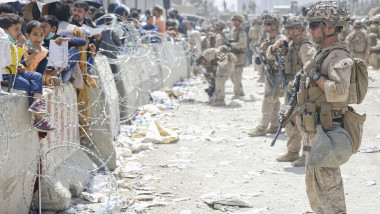 Soldați americani în fața unui zid cu sârmă ghimpată și civili afgani pe cealaltă parte