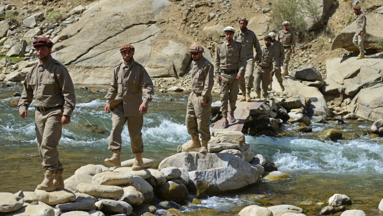 barbati in uniforma trec un rau pe o punte improvizata in valea panjshir