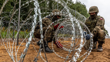 soldați polonezi întind sârmă ghimpată sub formă de barieră pentru a opri refugiați în august 2021