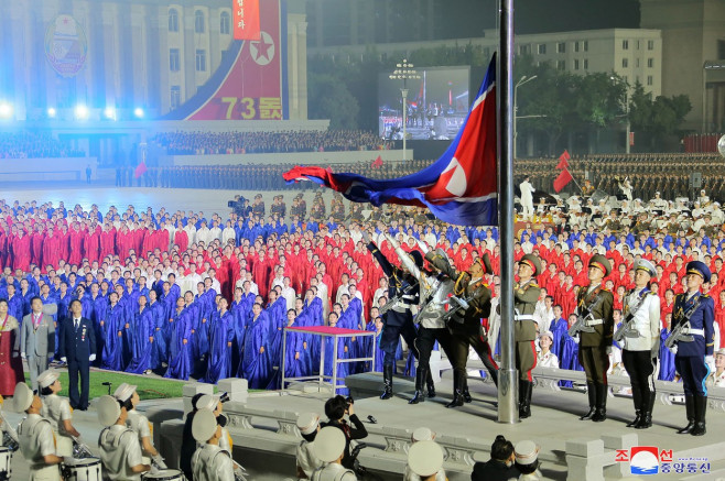 nord-coreeni cu steagul țării la aniversarea fondării statului