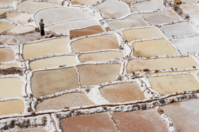 Single worker tends to his family salt plot at the Maras salt mines near Cusco, Peru