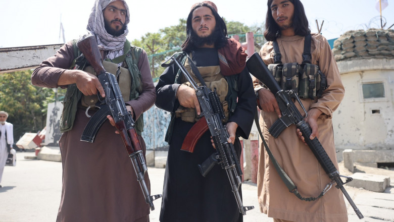 Bărbați afgani cu puști kalașnikov în mâini