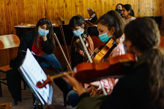 Fete cu mască de protecție exersează la instrumente muzicale