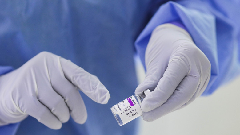 vaccin anticovid tinut in mana de o asistenta cu manusi albe