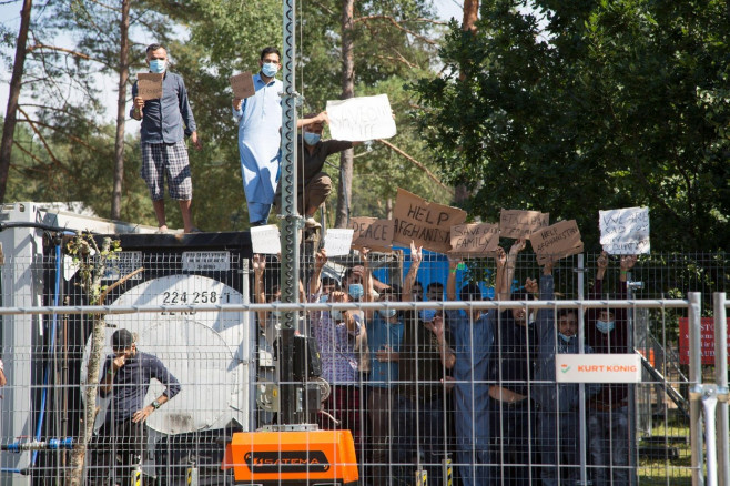 Rudninkai, Lithuania. 16th Aug, 2021. Migrants at the migrant camp in Rudninkai in Lithuania hold up placards with inscriptions such as "Help Afghanistan" and similar demands during a rally. (to dpa: "Refugees as a weapon" - Lithuania's border region with