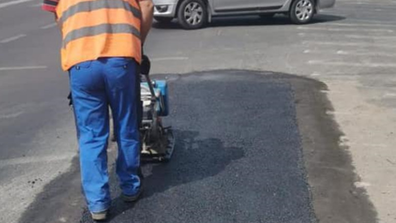 Un bărbat tasează o plombă de asflat pe stradă.