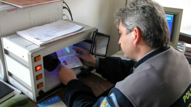 Un polițist de frontieră verifică un pașaport.