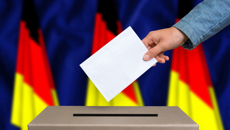 alegator care baga in urna buletinul de vot pe un fond cu steaguri ale germaniei