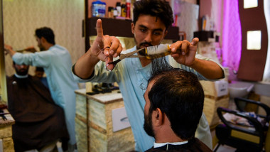 Un frizer tunde un client în orașul Herat din Afganistan.