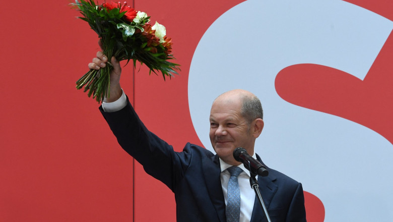 Ministrul german de finanțe, vicecancelarul și candidatul partidului social-democrat pentru funcția de cancelar al Germanei, Olaf Scholz, salută membrii social-democrați adunați luni dimineață la sediul din Berlin al SPD, în timp ce ține un buchet de flori în mână