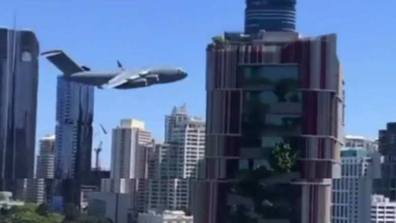 Un avion militar de transport zboară printre clădiri în Australia.