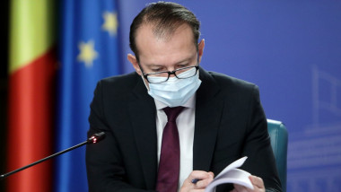 Florin Cîțu se uită pe niște documente într-o ședință de guvern.