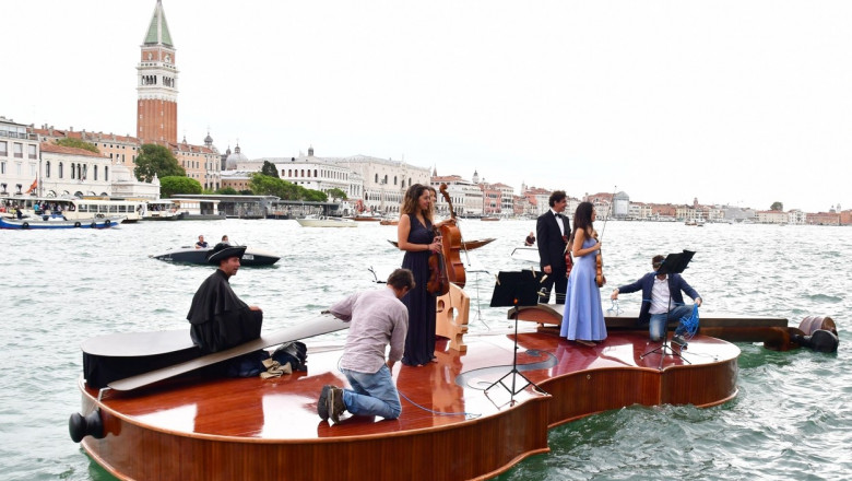 Un cvartet interpretează Vivaldi pe o barcă gigantică în formă de vioară, pe canalele Veneției.