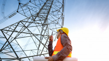 Construction worker checking location site near to High voltage tower.