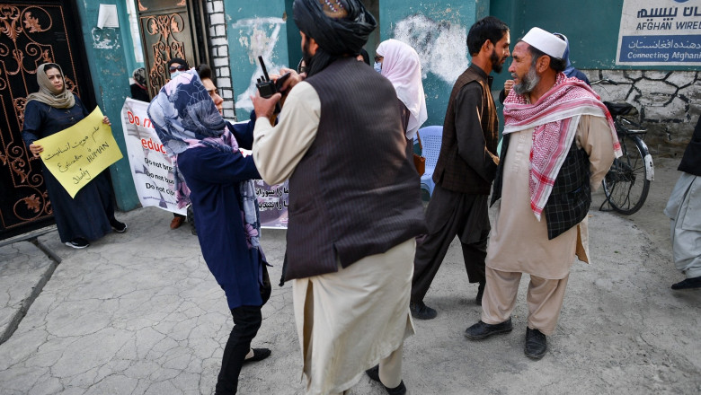 A woman protestor scuffles with a member of the Taliban during a demonstration outside a school in Kabul on September 30, 2021