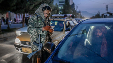 A member of the Taliban checks documents of people travelling in a car in Kabul on September 30, 2021
