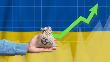 The concept of economic growth in Ukraine. Hand holds a bag with money and an upward arrow.