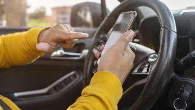 sofer ride-sharing care manevreaza un smartphone