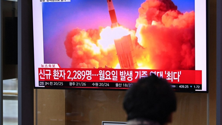 Un bărbat privește spre un televizor în care apare lansarea unei rachete balistice