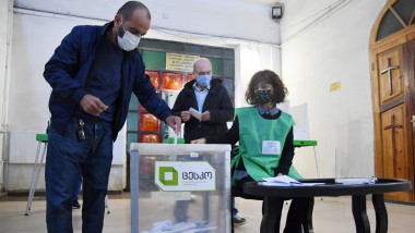 Bărbat cu mască votează la alegeri