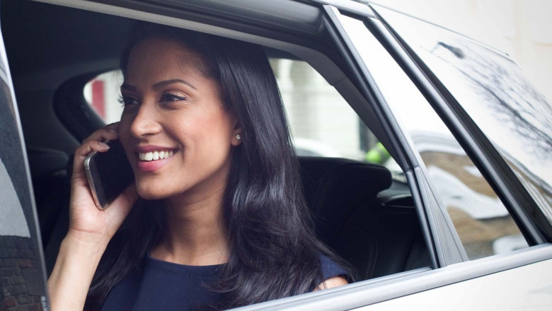 Business woman sitting in car, using smartphone