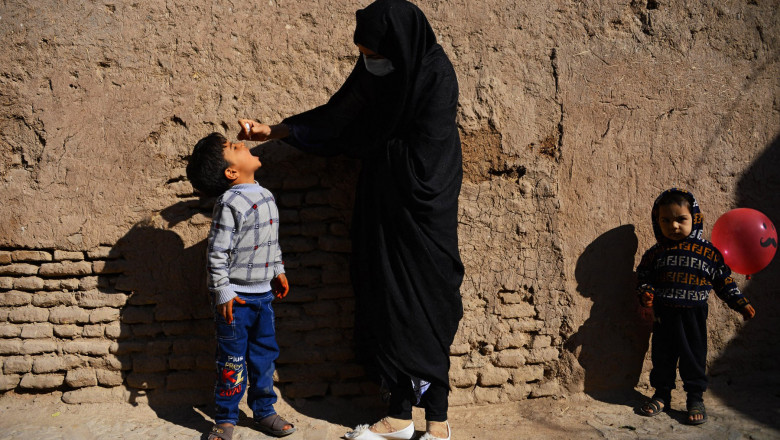 A burqa-clad health worker administers polio vaccine drops to a child during a vaccination campaign in the old quarters of Herat October 27, 2020