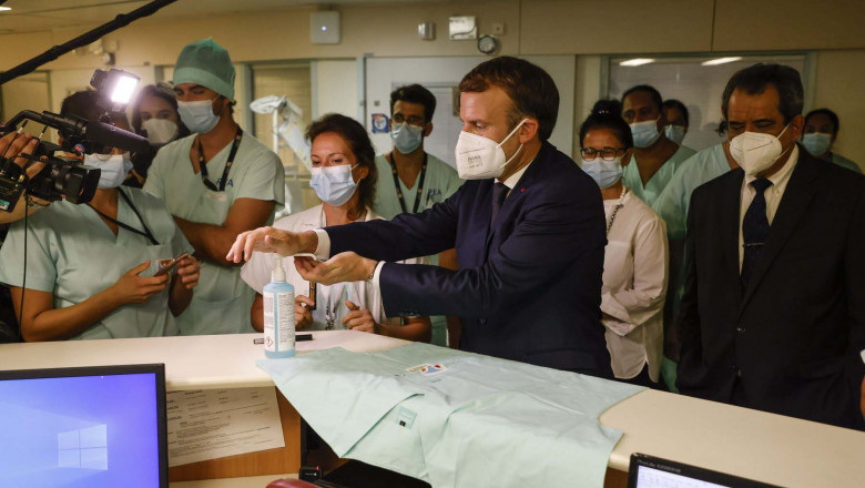 Emmanuel Macron (C) uses hand sanitiser before signing a nurse's vest as he meets with frontline staff working at the French Polynesia Hospital Centre in Papeete