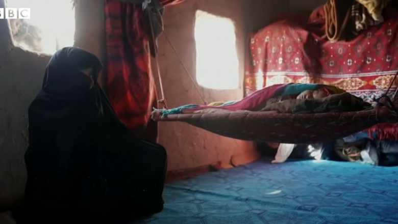 o femeie si un bebelus intr-o casa saraca din afganistan