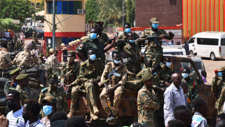Soldați stau pe un vehicul și privesc spre protestatari în Sudan