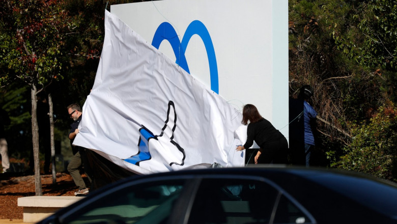 un angajat dezveleste un panou pe care este desenat noul logo al companiei Facebook