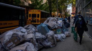 gramezi de gunoi si oameni pe trotuar in new york si autobuze galbene in spate