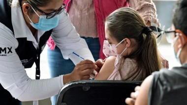 O asistentă vaccinează un copil cu un ser anti-Covid
