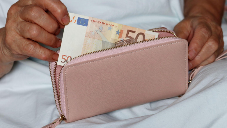femeie care scoate o bancnota de 50 de euro din portofel