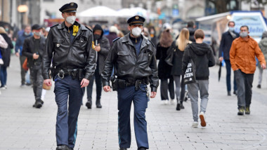 politisti cu masca si oameni pe o strada, in germania