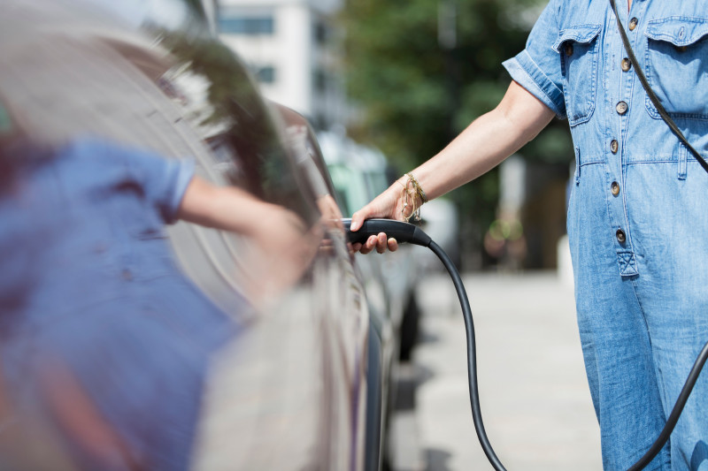 Woman recharging electric car