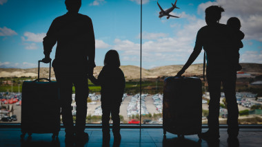 familie cu doi copii se uita pe geam la un avion care a decolat
