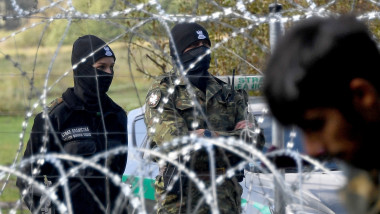 Polish border guards watch a refugee camp behind barbed wire installed on the border between Belarus and Poland near the village of Usnarz Dolny
