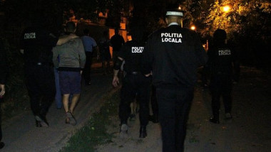politisti loclai escorteaza un barbat la sectie noaptea