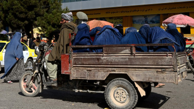 Burqa clad Afghan women travel on the back of a three-wheeler automobile in Mazar-i-Sharif on October 30