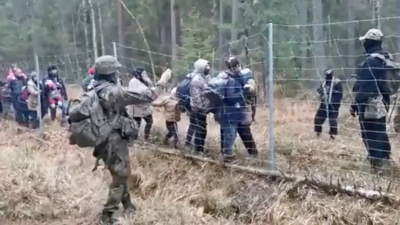 Migranți lângă un gard de sârmă ghimpată